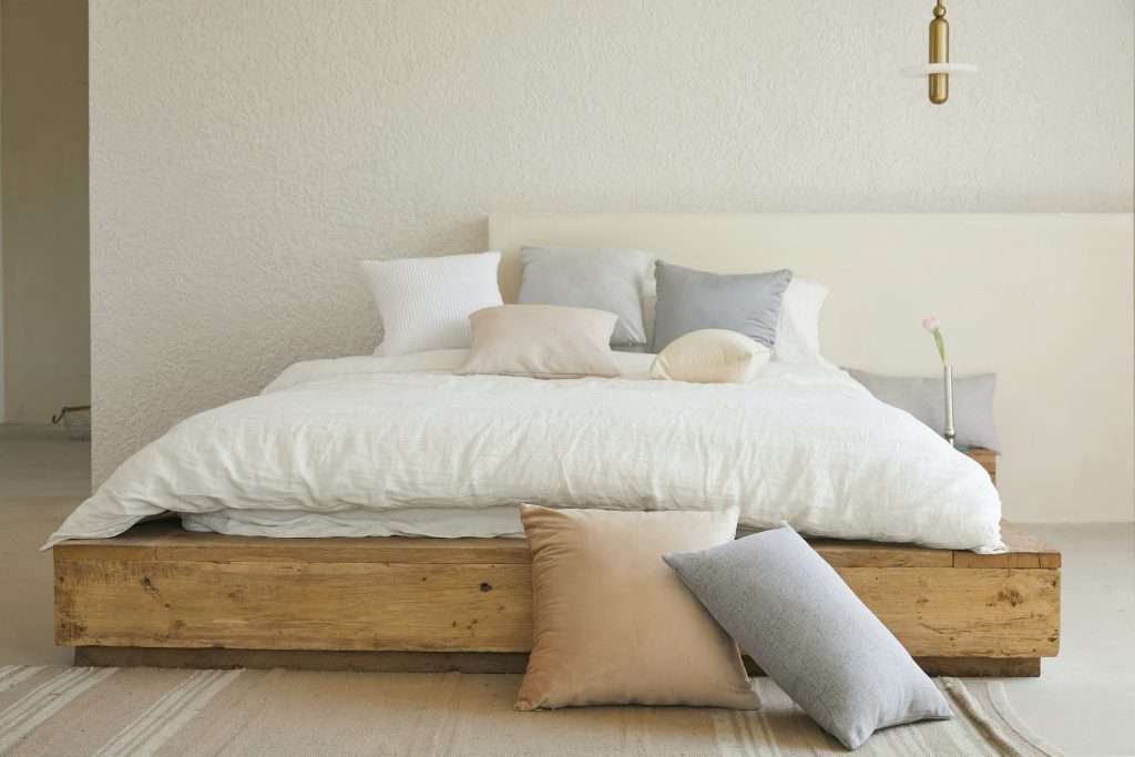 a minimalist interior with white pillows on a brown wooden bed